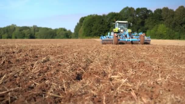 Traktorns baksida odlar stubbfältsjorden för sådd av spannmål — Stockvideo