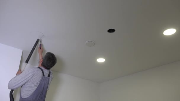 Byggare man såg runda hål i gipsskivor tak — Stockvideo