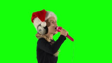 Mikrofonlu duygusal kız kulaklıkla şarkı söylüyor. Yeşil Ekran