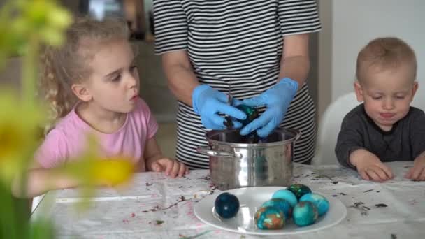 Niño y niña mirando a la abuela toman huevos de Pascua pintados de la olla. Gimbal. — Vídeos de Stock