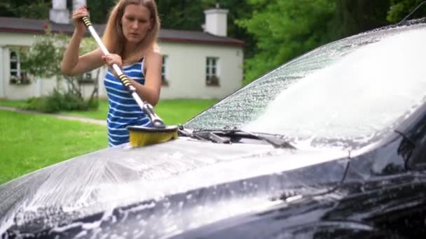 Liebevolle Frau bürstet Mann Motorhaube mit langer Bürste Shampoo im Hof des Hauses — Stockvideo