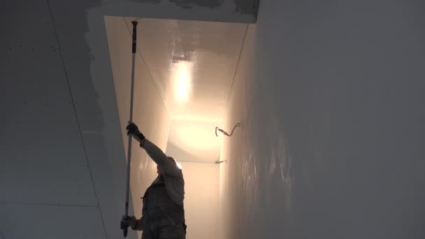 Whitewasher pintor homem com rolo de vara de pintura no teto de pintura mão em branco — Vídeo de Stock