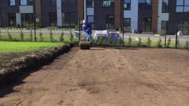 Çimen tohumu ektikten sonra toprağı sıkıştıran yetenekli işçi. Statik çekim