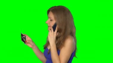 Kadın telefonda konuşuyor, elinde hamilelik fotoğrafı var. Krom anahtar ekranı. 4K
