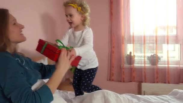 Fille donnant boîte cadeau à sa mère. Maman est couchée dans la chambre. 4K — Video