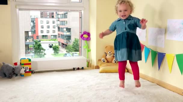 Bebé danza infantil en la habitación de los niños decorados de colores. 4K — Vídeos de Stock