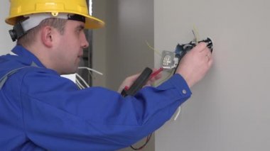Elektrikçi özel bir aletle prizleri kontrol ediyor. 4K