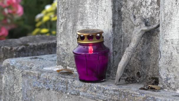 Крупный план горящей фиолетовой свечи и маленькой распятой фигурки Иисуса. 4K — стоковое видео