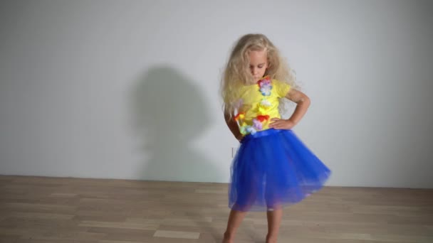 金髪の巻き毛の女の子が部屋で楽しいダンスをしている。遊び心のある子供の笑顔 — ストック動画