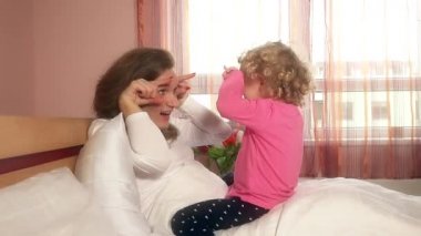 Anne kıvırcık kızıyla yatakta oynuyor. 4K