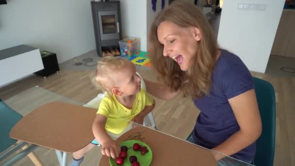 Buen niño, alimenta a su madre con bayas de cereza. Movimiento suave de la cámara — Vídeo de stock
