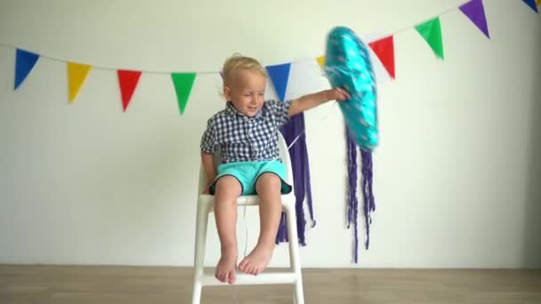 Ragazzo che festeggia il secondo compleanno. bambino sulla sedia con palloncino. Movimento di Gimbal — Video Stock