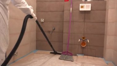 İşçi erkek, döşeme üstüne banyo süpürüyor. Yeni konutların tamiri. 4K