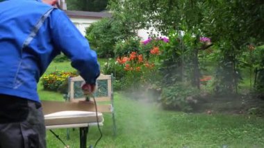 Adam bahçede hobi olarak iş yapıyor. Öğütücü aletler, toz maskesi ve gözlük kullanıyor