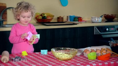 Küçük kız mutfak masasında bisküvi kalıplarıyla oynuyor. 4K