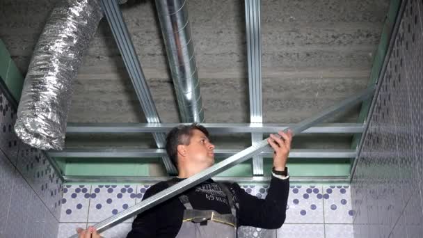 Профессиональные рабочие закрепляют потолочные профили в новой ванной комнате — стоковое видео