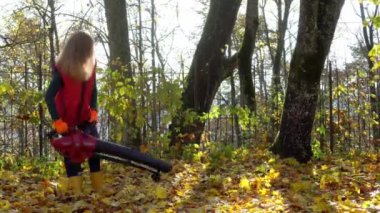 Kırmızı ceketli, sarı çizmeli, güz yapraklı işçi kadın.