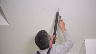 İnşaat işçisi ışıklandırma için alçı taşı tavanında delikler açıyor