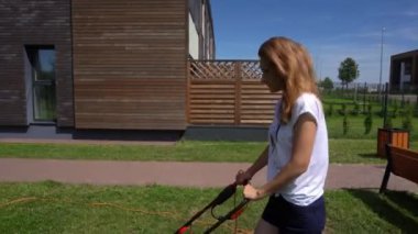 Kız evin bahçesinde elektrikli çim biçme makinesiyle çim biçiyor. Gimbal hareketi