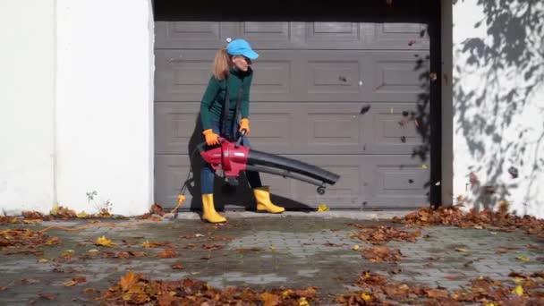 Moglie soffiare foglie da marito garage ingresso in autunno. — Video Stock