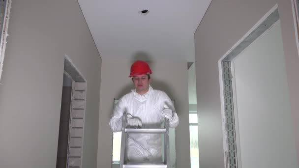 Homem de pé na escada fazer buraco para iluminação LED em nova casa. 4K — Vídeo de Stock
