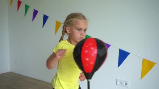 En liten flicka som slår slående boxningspäron. Gimbal rörelse — Stockvideo
