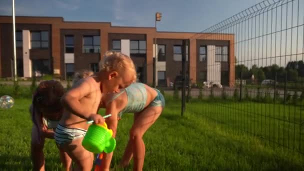 Ruiva e loiras irmãs jogando jogos de água com o irmãozinho — Vídeo de Stock