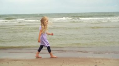 Deniz kıyısında yürüyen güzel sarışın kız. Kıvırcık saçlı sevimli çocuk.