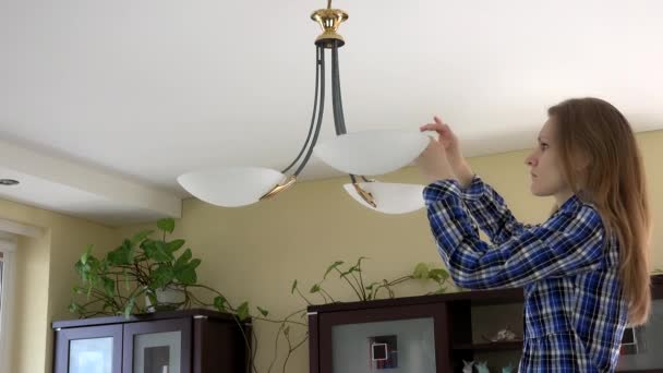 Женщина меняет лампочку в помещении квартиры. 4K — стоковое видео