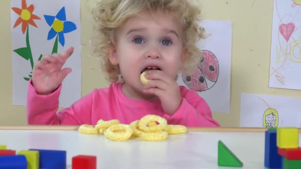 A lány kukoricát eszik az asztalon. Együttérző, göndör, kék szemű lány. 4K — Stock videók