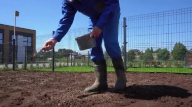 Tanımlanamayan bir adam özel apartman bahçesinde çimen ekiyor..