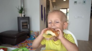 Aç çocuk bir kadınla büyük hamburger yiyor. Gimbal kamera hareketi