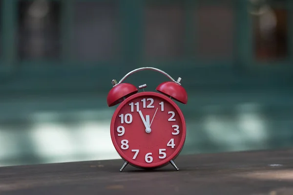 Retro alarm clock with five minutes to twelve o\'clock.