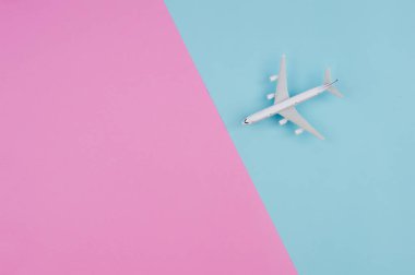 Düz minyatür oyuncak uçak pembe üzerinde yatıyordu ve sarı arka plan