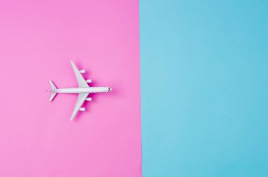 Düz minyatür oyuncak uçak pembe üzerinde yatıyordu ve sarı arka plan