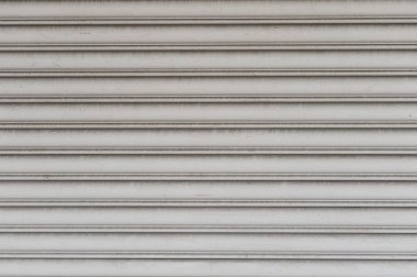 Fabrikada, depoda, garajda ve endüstriyel depoda kullanılan otomatik metal paten kapısının yakın çekimi. Bükülebilir ve katlanabilir metal levha yer tasarrufu sunuyor ve kentsel ve kırsal hissi sağlıyor