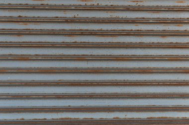 Fabrikada, depoda, garajda ve endüstriyel depoda kullanılan otomatik metal paten kapısının yakın çekimi. Bükülebilir ve katlanabilir metal levha yer tasarrufu sunuyor ve kentsel ve kırsal hissi sağlıyor