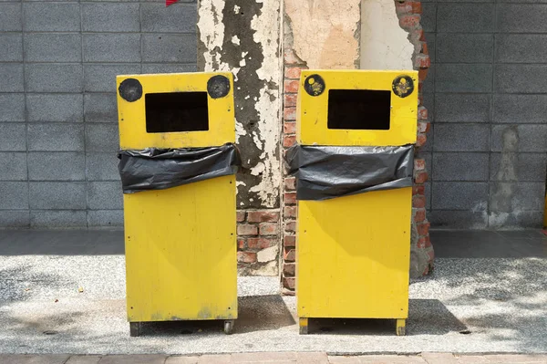 Two yellow city trash cans