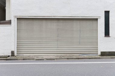 Fabrikada, depoda, garajda ve endüstriyel depoda kullanılan otomatik metal paten kapısının yakın çekimi. Bükülebilir ve katlanabilir metal levha yer tasarrufu sunuyor ve kentsel ve kırsal hissi sağlıyor