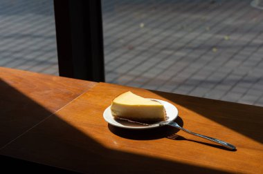 Dilimlenmiş New York Cheesecake beyaz tabakta ahşap arka planda