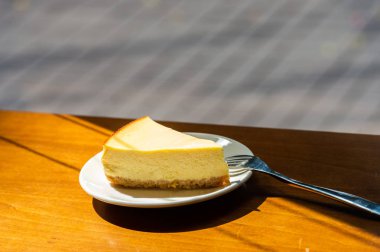 Dilimlenmiş New York Cheesecake beyaz tabakta ahşap arka planda