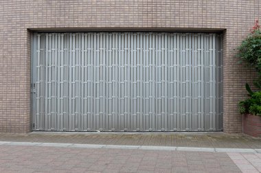 Fabrikada, depoda, garajda ve endüstriyel depoda kullanılan otomatik metal paten kapısının yakın çekimi. Bükülebilir ve katlanabilir metal levha yer tasarrufu sunuyor ve kentsel ve kırsal hissi sağlıyor