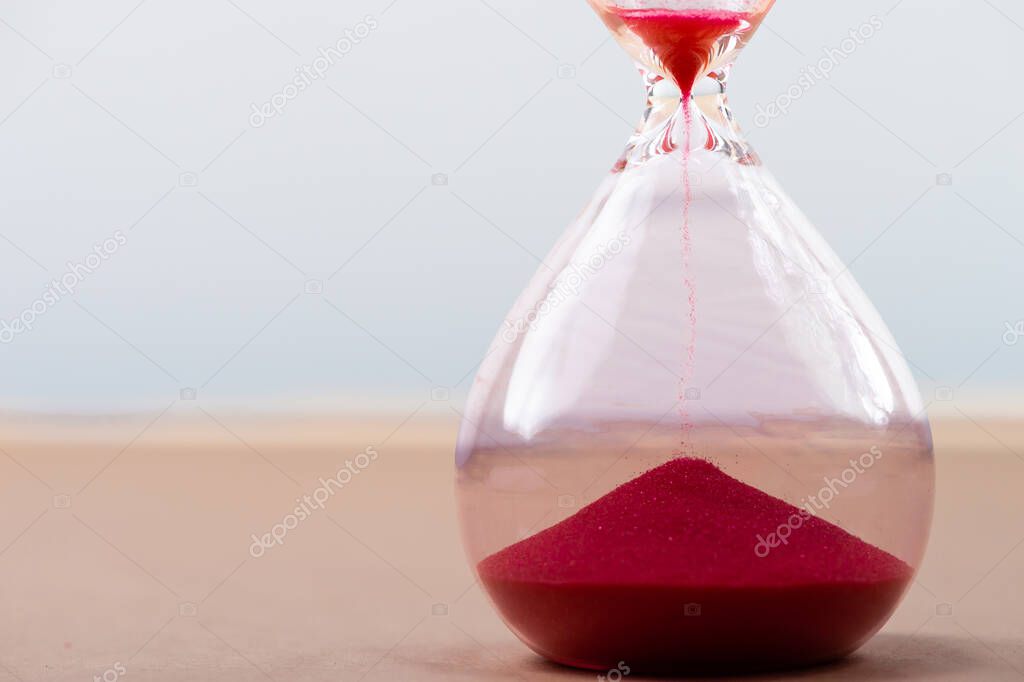 Hourglass with flowing sand on table. Time management