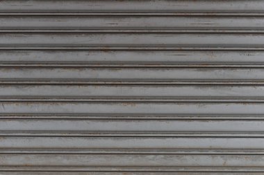 Fabrikada, depoda, garajda ve endüstriyel depoda kullanılan otomatik metal paten kapısının yakın çekimi. Bükülebilir ve katlanabilir metal levha yer tasarrufu sunuyor ve kentsel ve kırsal hissi sağlıyor