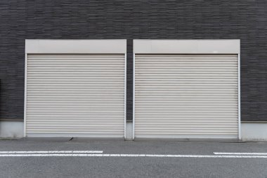 Fabrikada, depoda, garajda ve endüstriyel depoda kullanılan otomatik metal paten kapısının yakın çekimi. Bükülebilir ve katlanabilir metal levha yer tasarrufu sunuyor ve kentsel ve kırsal hissi sağlıyor