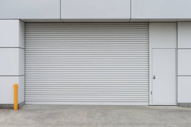 Fabrikada, depoda, garajda ve endüstriyel depoda kullanılan otomatik metal paten kapısının yakın çekimi. Bükülebilir ve katlanabilir metal levha yer tasarrufu sunuyor ve kentsel ve kırsal hissi sağlıyor