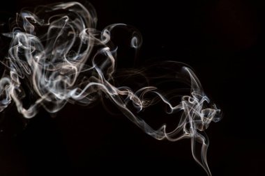 Siyah arkaplanda beyaz dumanı yakma hareketinin soyut güzel bir parçası.