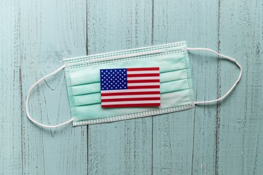 Ahşap masa arkasında tıbbi yüz maskesi, tahta arka planda yeşil yüz maskesi seçici odak.