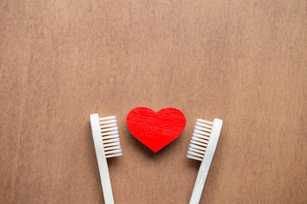 Bamboo toothbrushes and wooden heart on vintage wood background. Family set of biodegradable natural bamboo toothbrushes. Zero waste, eco-friendly, plastic free concept. Flat lay with copy space.