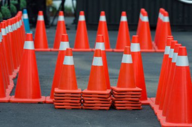 Koyu asfalt üzerinde parlak turuncu trafik konileri